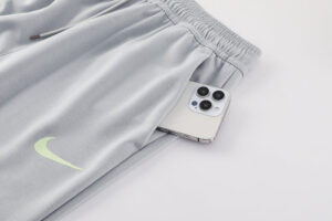 Gray Nike sweatpants with a lime swoosh, showing a smartphone tucked in the pocket.