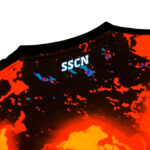 Close-up of a black T-shirt with a fiery orange-red lava pattern and a small blue 'SSCN' logo near the neckline.