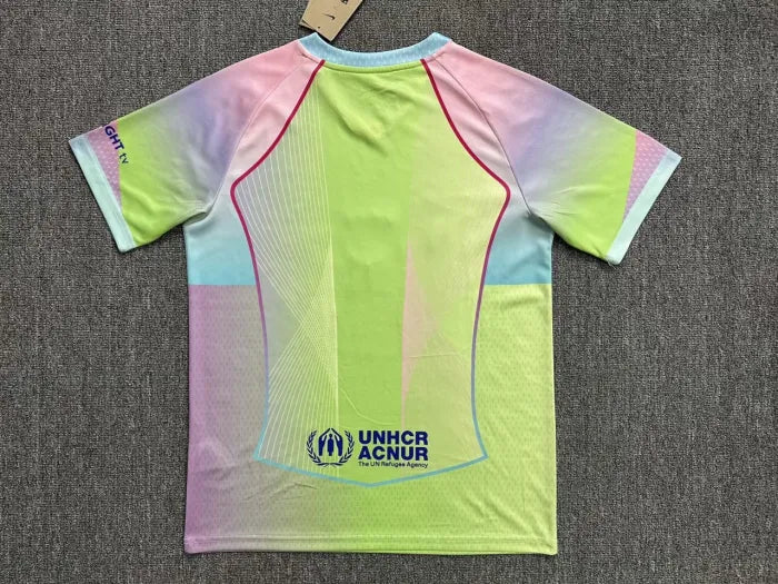Back view of a bright multi‑color athletic jersey with neon yellow, pink, blue and purple panels and pink piping, featuring UNHCR logo at the lower back.