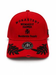 917f6c86-09a4-43c7-9976-09c99a0970aa_c58f02dc-db08-4782-b651-4bb96c32c107 | UAE SPORT STORE Red baseball cap with black embroidery reading 'MONASTERY WE MAKE IT HAPPEN Worldwide Supply' and floral leaf accents on the brim.