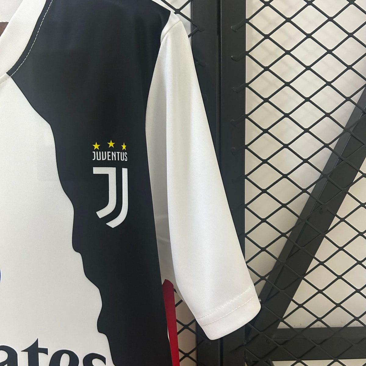 Juventus football jersey hanging on a rack, black and white panels with three yellow stars above 'JUVENTUS' text.