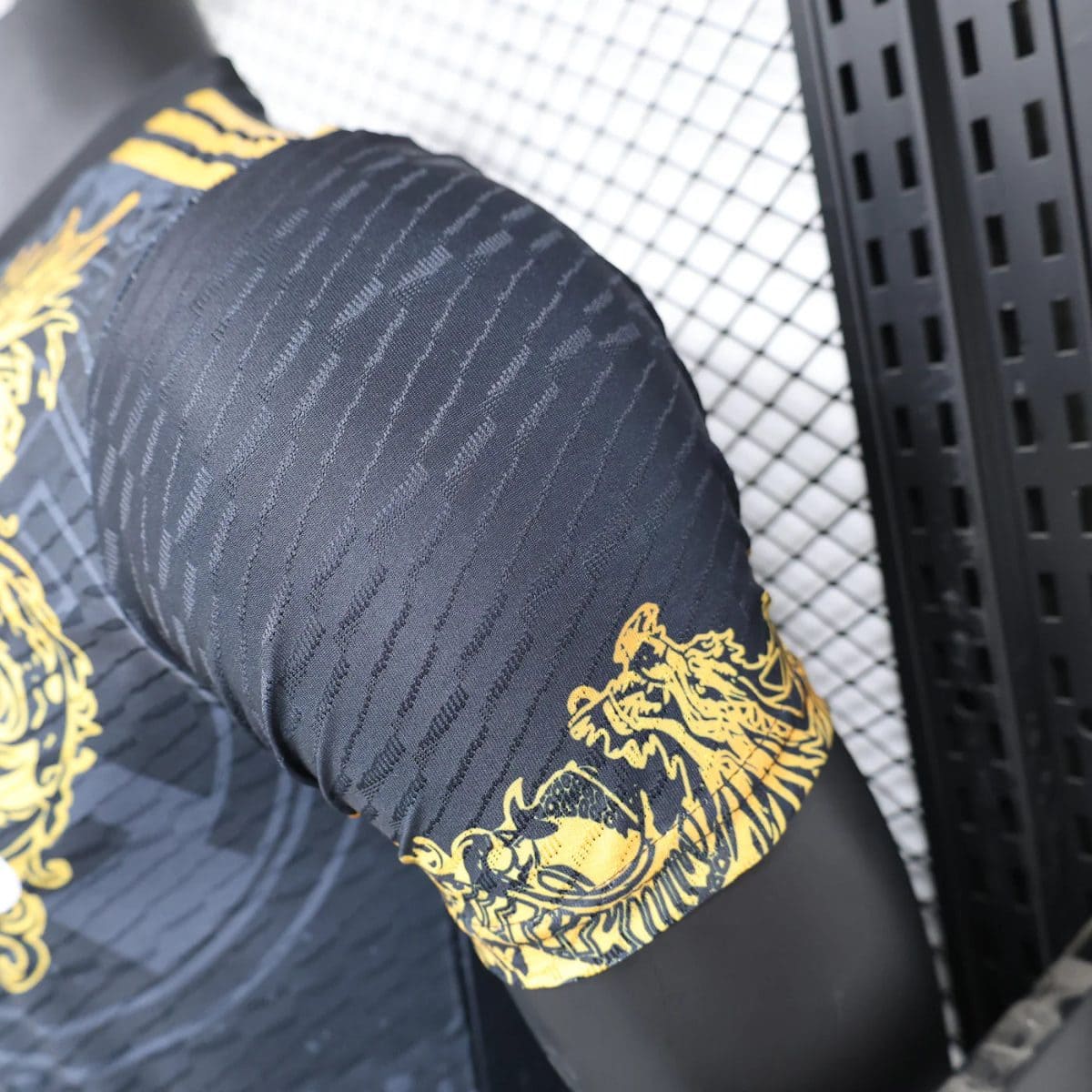 Close-up of a black athletic sleeve with subtle diagonal stripes and a yellow dragon graphic at the cuff.