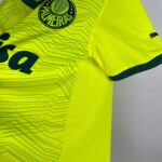 Close-up of a neon yellow high-visibility sports jersey showing a circular team badge and a Puma logo nearby.