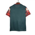 Back view of a teal sports jersey with red printed sleeves hanging on a wooden hanger, product display.