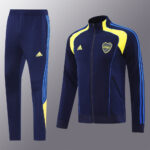 926025e2 | UAE SPORT STORE Navy blue Adidas tracksuit: zip-front jacket with yellow panels and side stripes, matching pants with blue stripes.