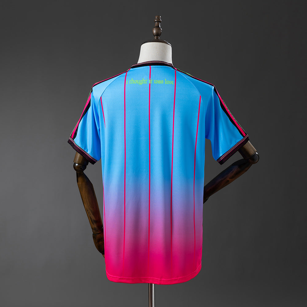 92b91cae | UAE SPORT STORE Back view of a blue-to-pink gradient sports jersey with pink vertical stripes and yellow text near the collar that reads, "i thought it was love."