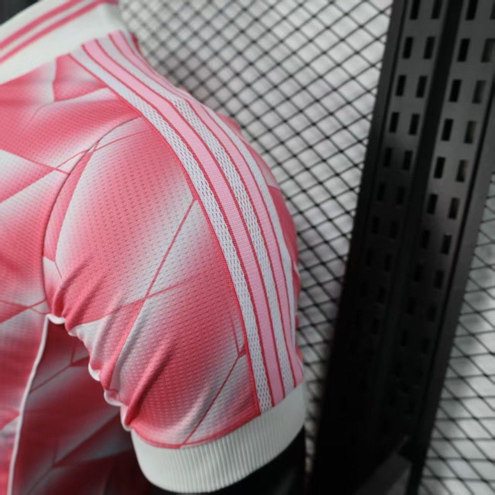 93afbfa9-4d3f-45e0-8ccf-63bf6f0d03b8 | UAE SPORT STORE Close-up of a pink sports jersey sleeve with white stripes, against a chain-link fence background.