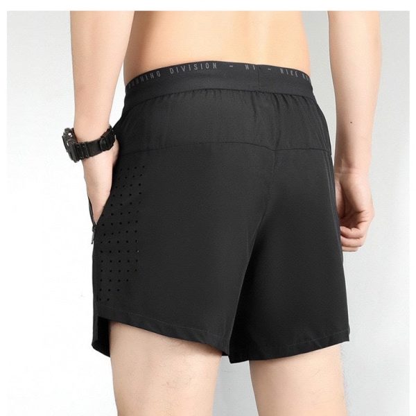 Back view of a person wearing black athletic shorts with mesh perforations on the side panels and an elastic waistband. A watch is on the left wrist.
