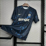 Chelsea FC dark blue away jersey with BingX sponsor, Nike swoosh, and club crest hanging on a rack.