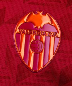 Close-up of the Valencia CF crest on a red jersey, featuring the bat and football motif.