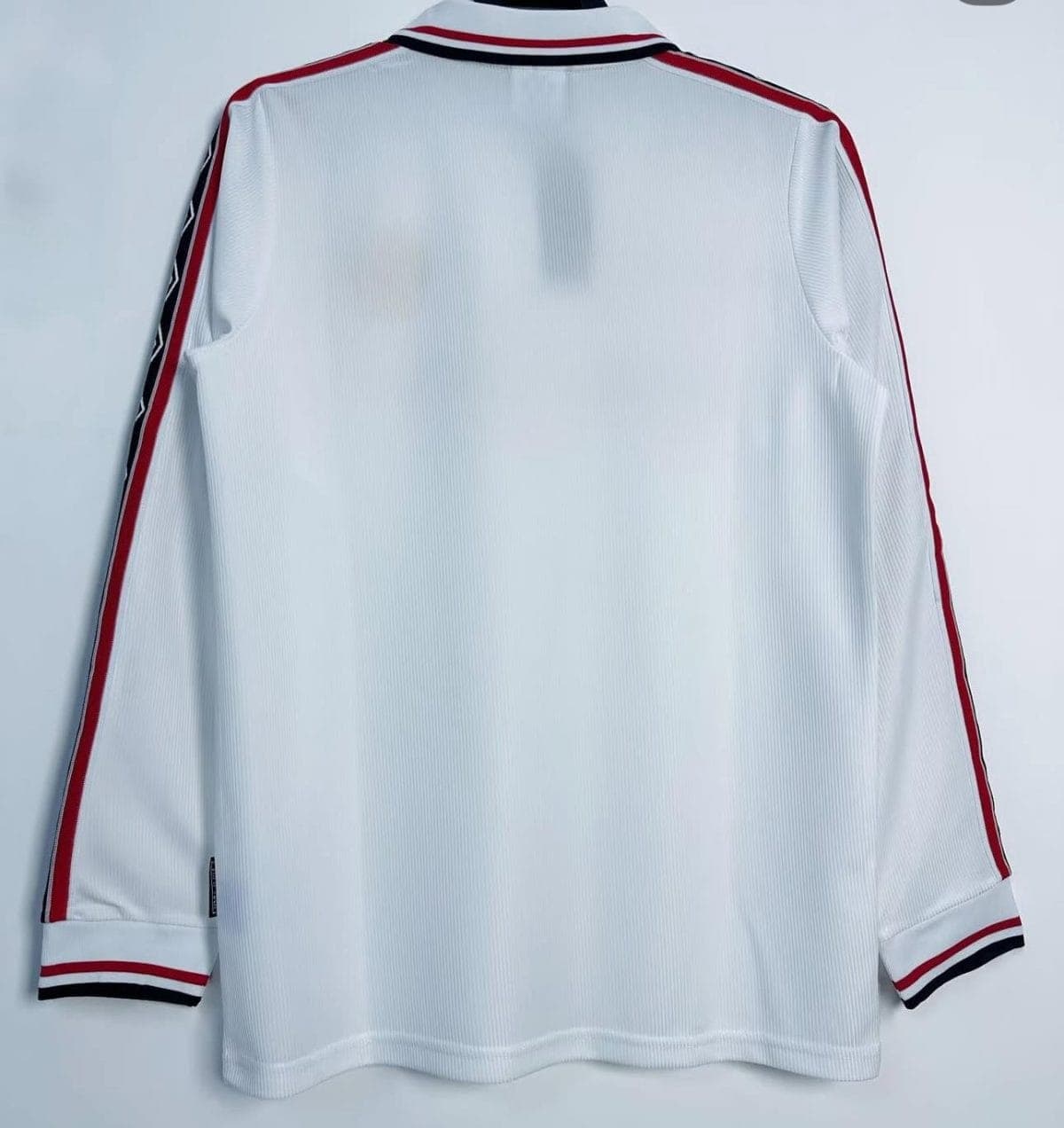 White athletic jacket seen from the back with red and black striped trim along the sleeves and collar.