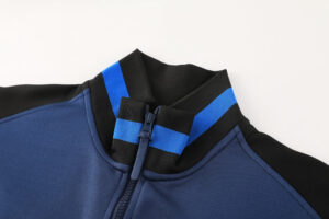 97119eb1 | UAE SPORT STORE Close-up of a blue zip-front jacket showing a black and blue striped ribbed collar.