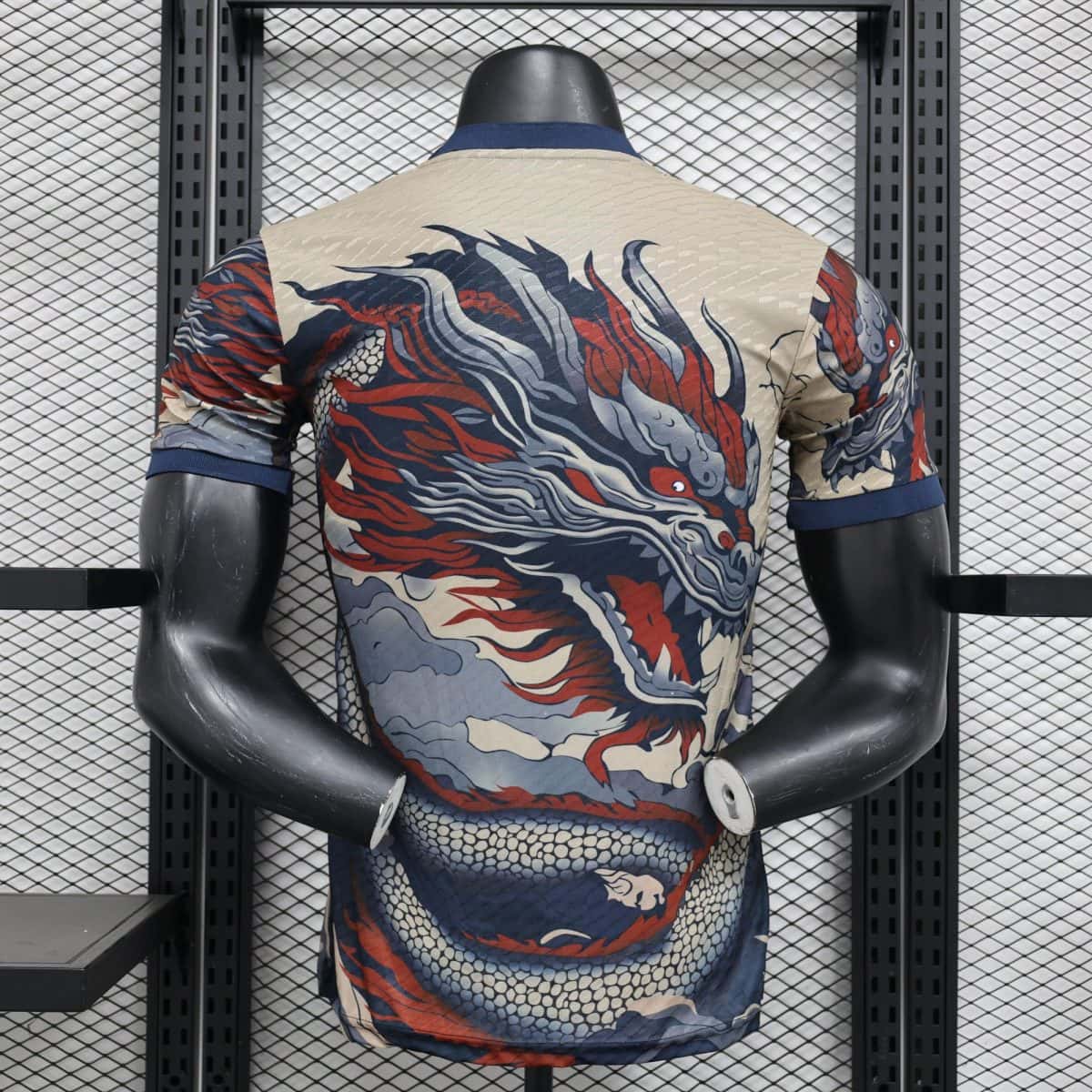 Back view of a mannequin wearing a beige dragon-pattern shirt, standing in front of a metal grid rack.