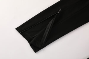 Close-up of black pants leg with ankle zipper partially opened.