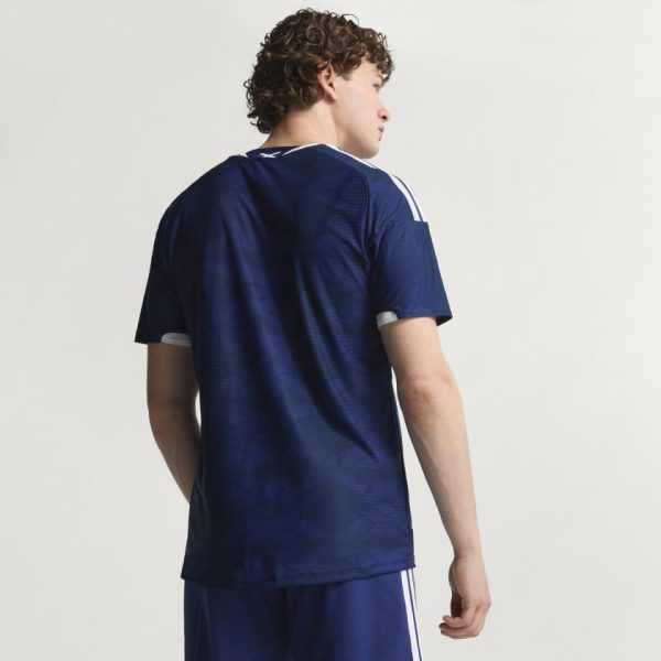Person in navy blue sports jersey shown from behind, white trim on sleeves, dark blue shorts.