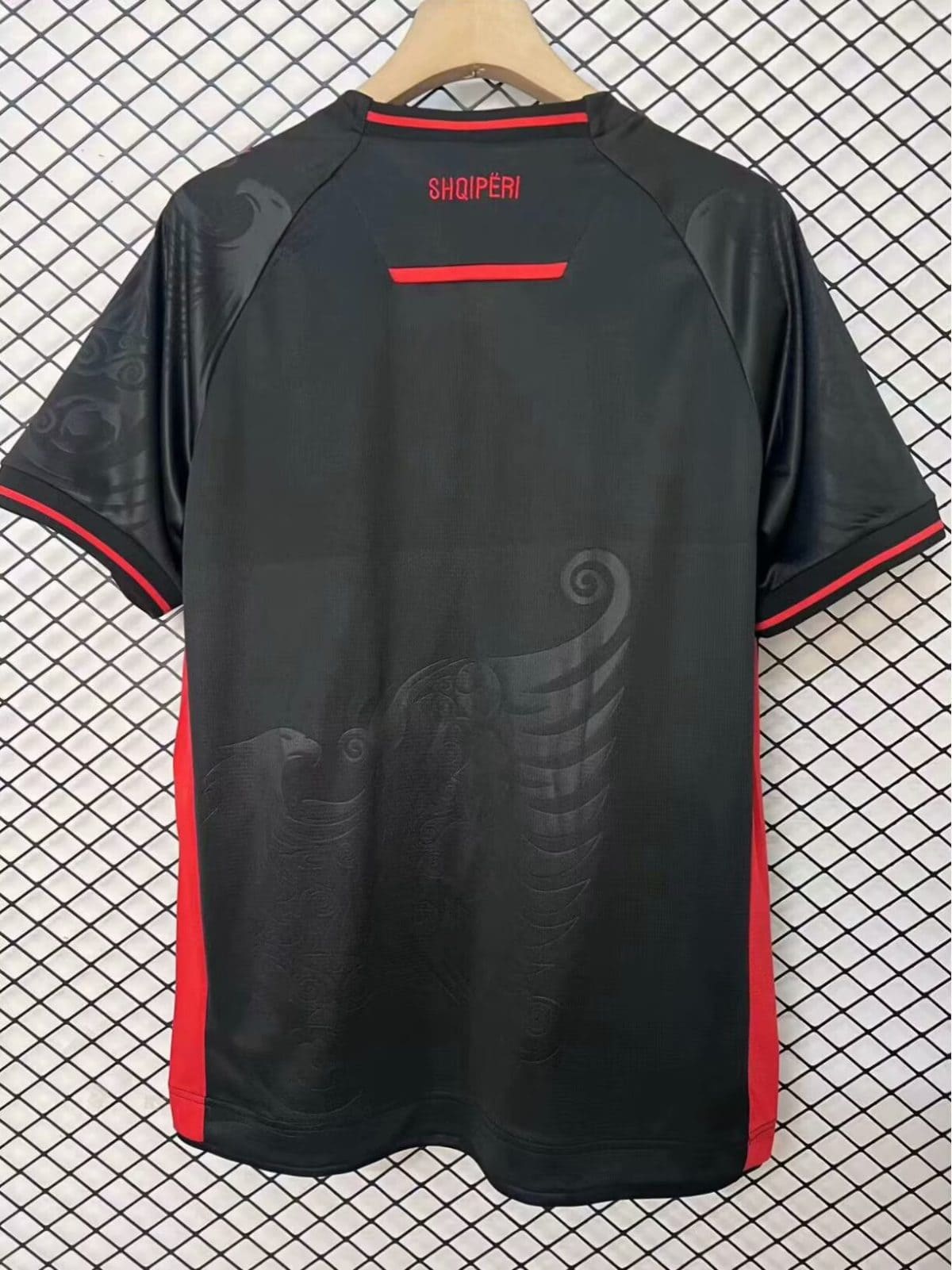 Black athletic jersey shown from the back with red trim on collar and sleeves, and 'SHQIPËRI' text at the neck; subtle embossed swirl pattern on the fabric.