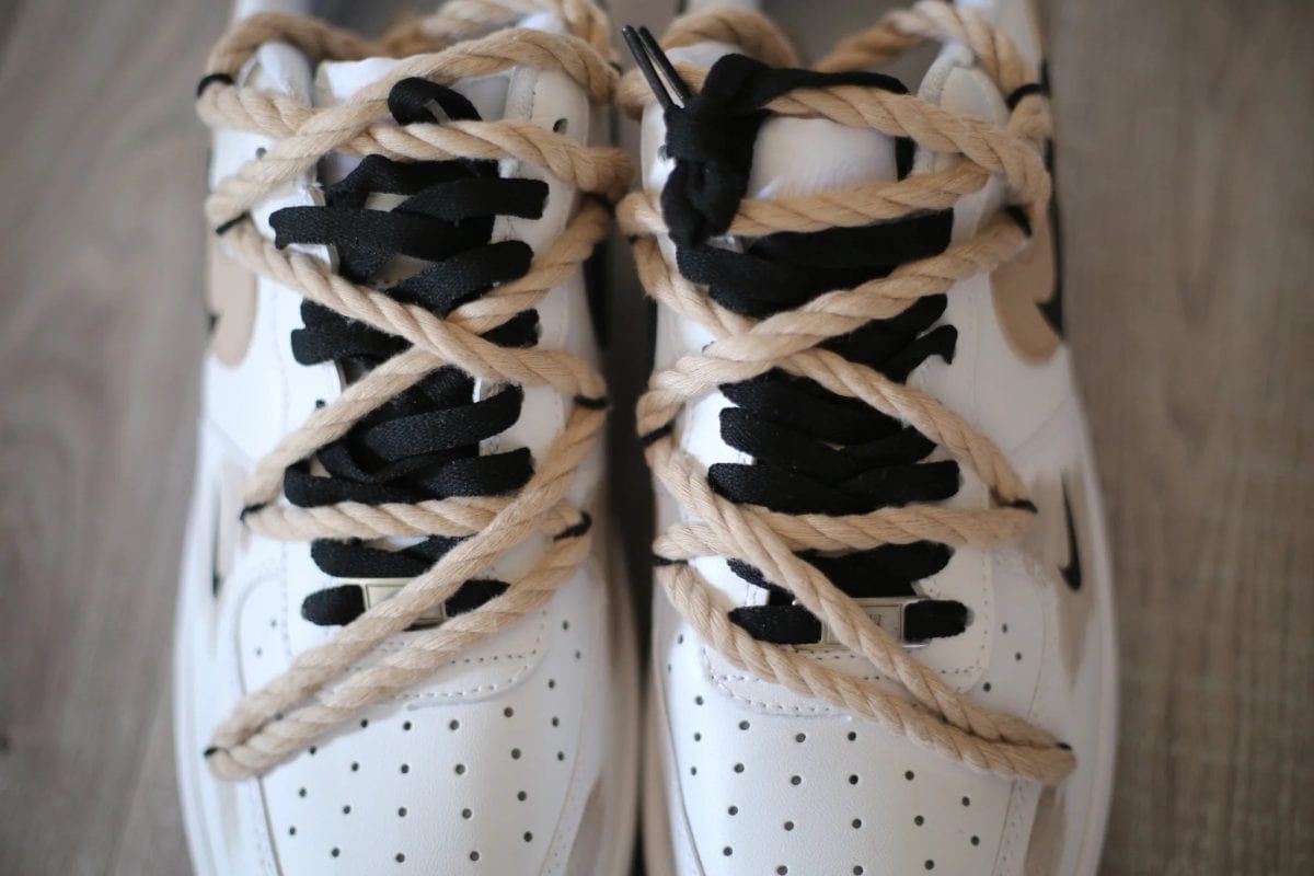 Close-up of white perforated sneakers with beige shoelaces wrapped around them, shot from above.