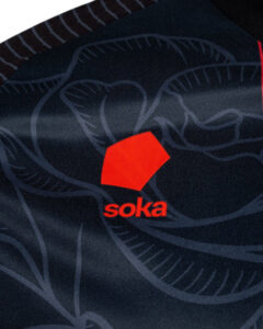 Close-up of dark navy fabric featuring a red geometric logo and the word 'soka' beneath it.