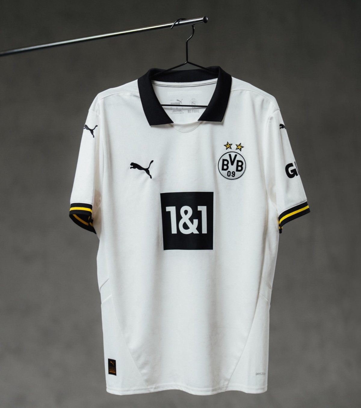 White Borussia Dortmund soccer jersey on a hanger, black collar, BVB crest with two gold stars, and 1&1 sponsor on the front.