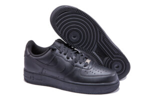 Black Nike Air Force 1 sneakers, one shoe facing forward with the other showing its sole on a white background.