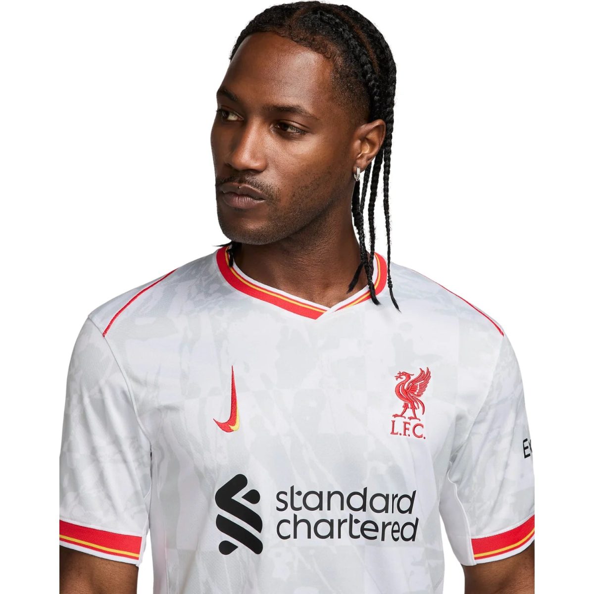 Portrait of a man wearing a white Liverpool FC jersey with red crest and 'Standard Chartered' sponsor logo visible on the chest.