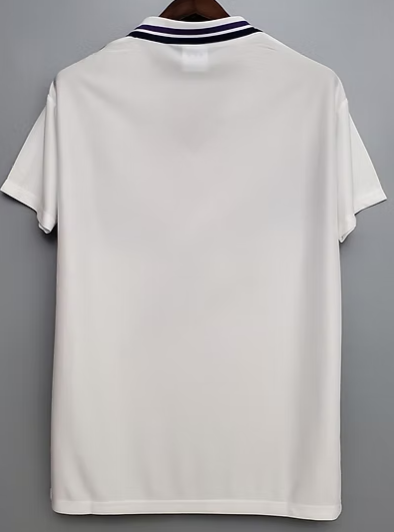 White polo shirt shown from the back, hanging on a hanger, with a navy striped collar