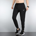 Man wearing black Nike joggers with a drawstring waist, taper cuffs, and side pockets, paired with black Nike sneakers