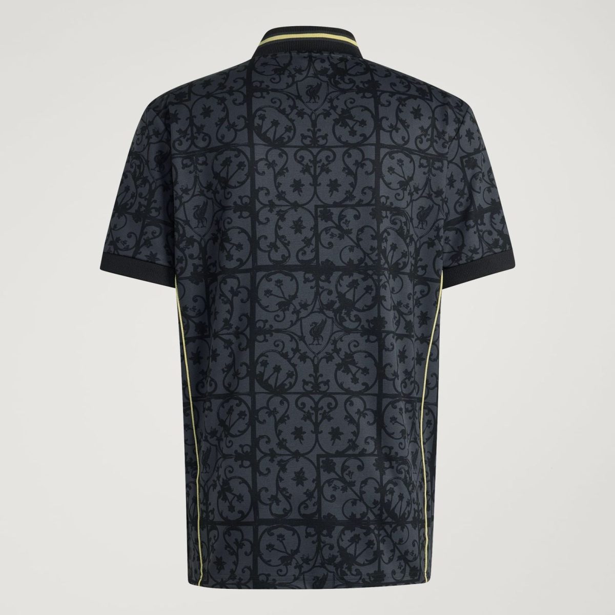 Back view of a dark polo shirt with an ornate floral lattice pattern and pale-yellow piping along the seams and collar edge.