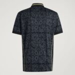 Back view of a dark polo shirt with an ornate floral lattice pattern and pale-yellow piping along the seams and collar edge.