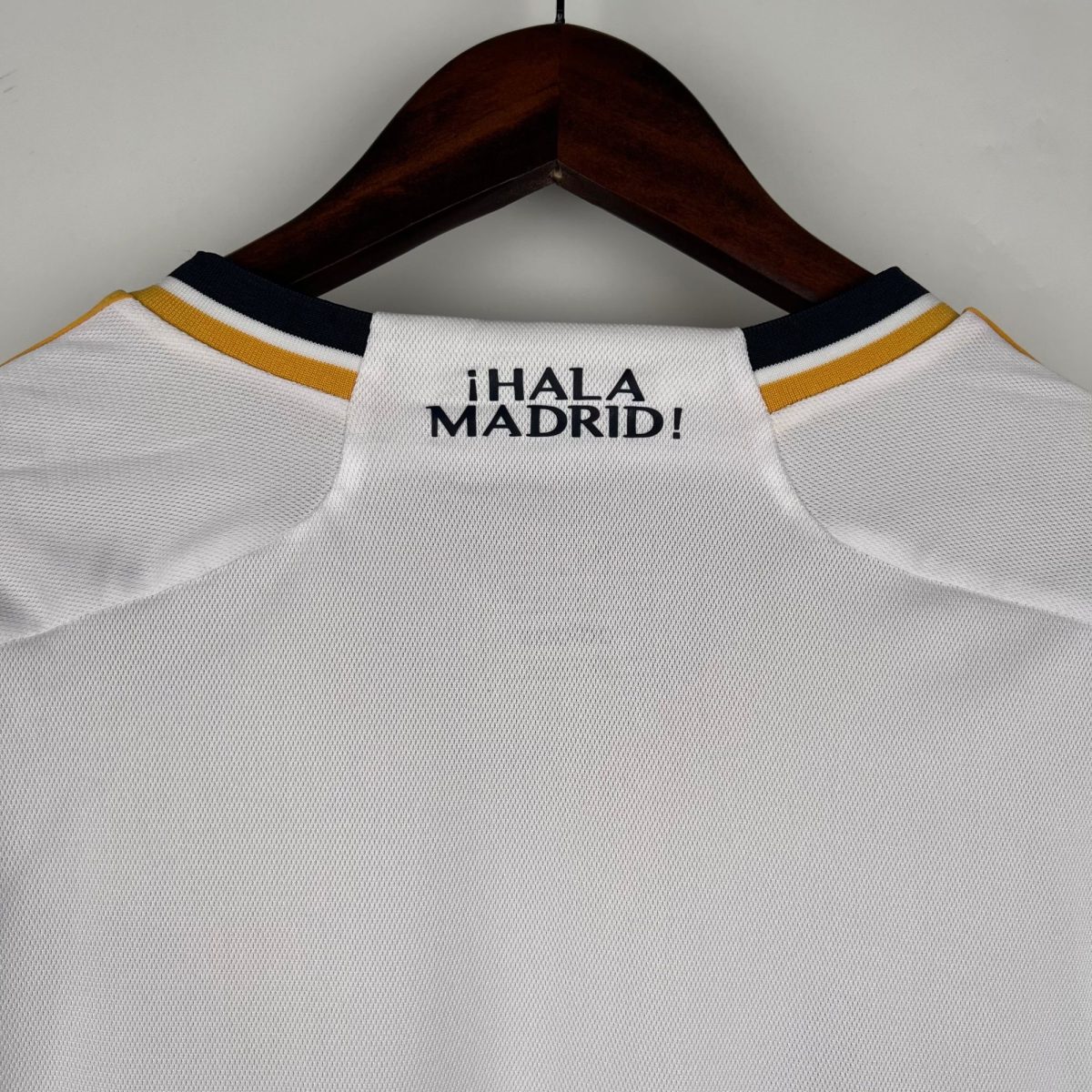 White textured sports jersey on a wooden hanger, with the text '¡HALA MADRID!' visible near the neckline.