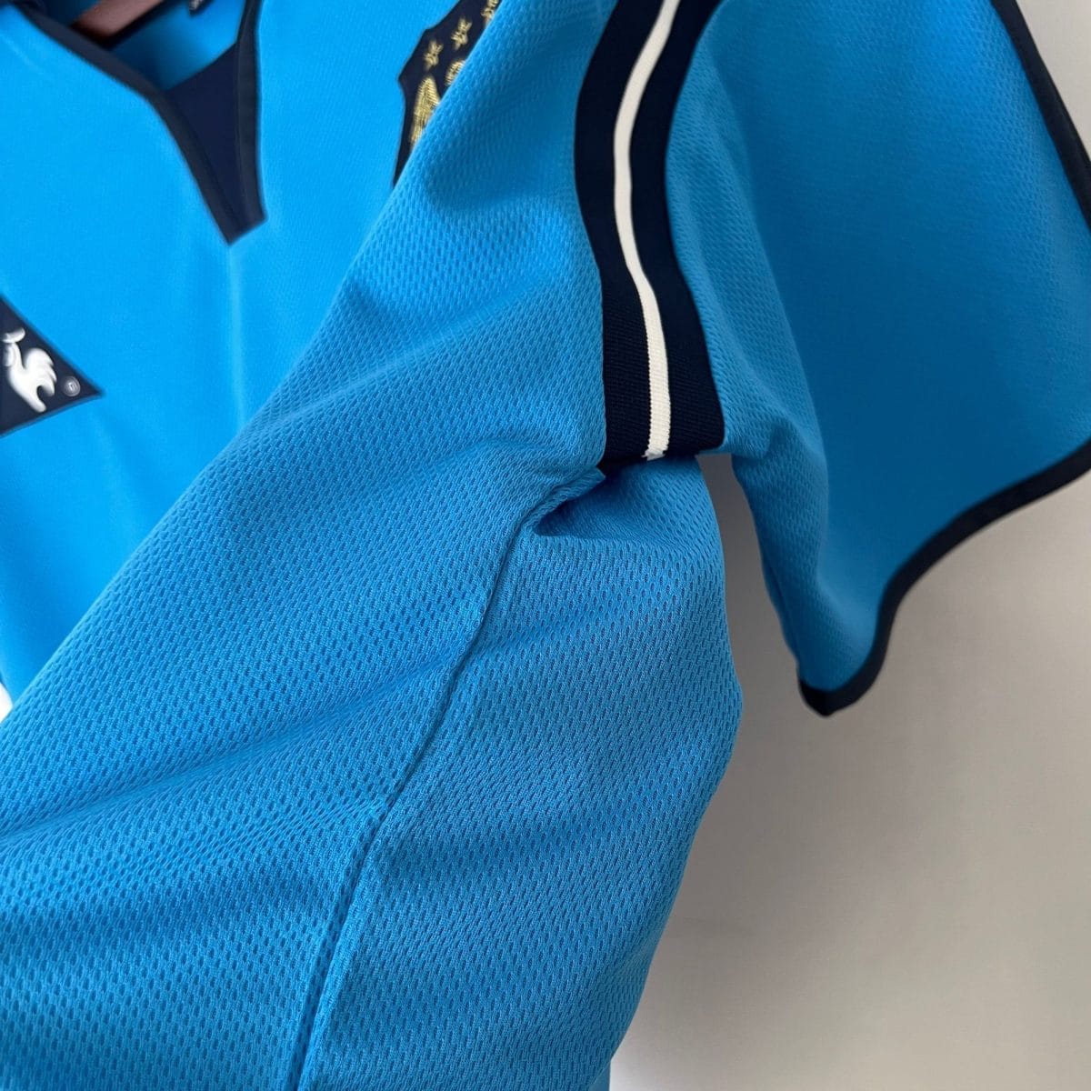 Close-up of bright blue mesh fabric with a black zipper and white trim on a sports jacket.