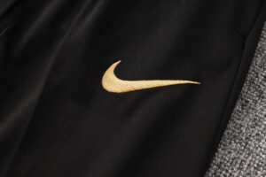 Close-up of black fabric featuring a gold Nike swoosh logo near the seam