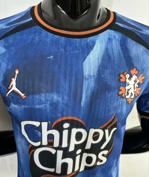 9d1fda0be8eb1c49 | UAE SPORT STORE Blue soccer jersey on a mannequin with orange-trim neck, showing Jumpman logo on the left chest, a lion crest on the right, and 'Chippy Chips' sponsor text.