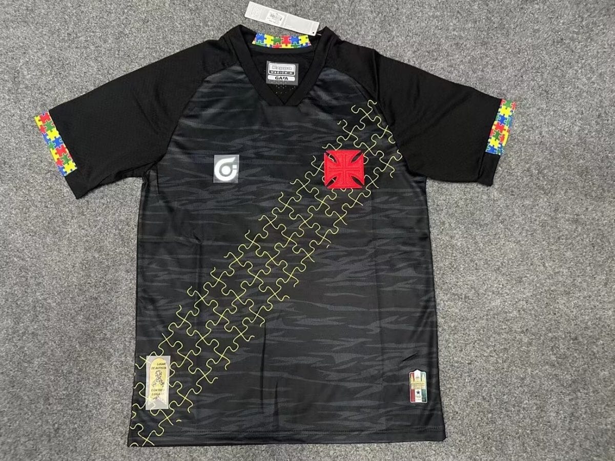 Black athletic jersey with yellow puzzle-piece diagonal pattern and colorful sleeve trim; features red crest patch and small patches near hem.
