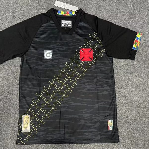 Black athletic jersey with yellow puzzle-piece diagonal pattern and colorful sleeve trim; features red crest patch and small patches near hem.