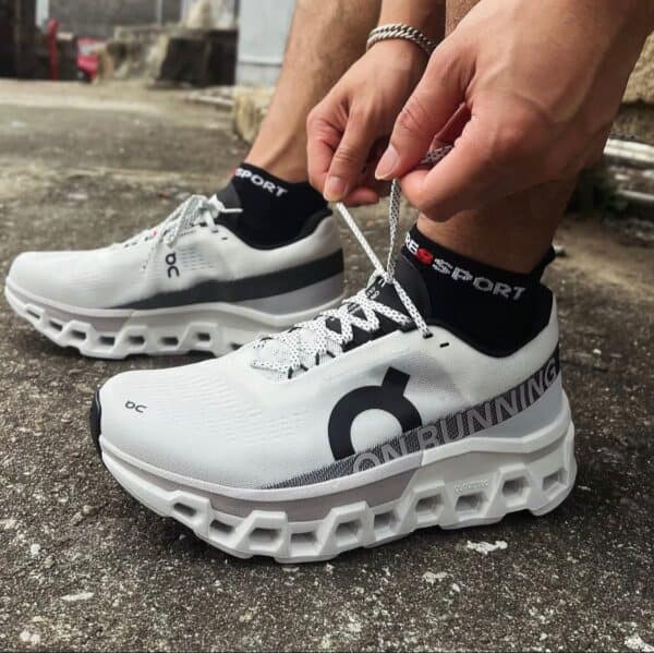 Running Cloudmonster 2 sneakers for men, white with black accents, on outdoor pavement.