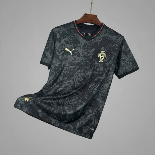 Dark gray camouflage Portugal national football team jersey by Puma, with a gold crest on the left chest and the gold Puma logo on the right, hanging on a wooden hanger.