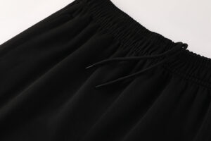 Close-up of a black elastic waistband with a drawstring on smooth fabric shorts.
