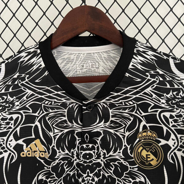 Black-and-white Real Madrid jersey on a wooden hanger with gold Adidas logo and club crest, against a diamond lattice backdrop.