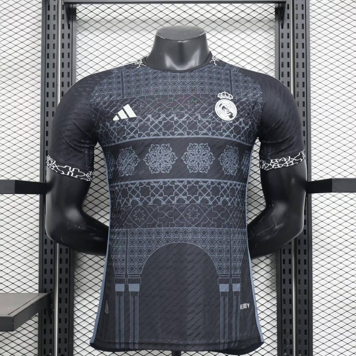 Mannequin wearing a dark Real Madrid football jersey with geometric patterns, Real Madrid crest, and Adidas logo on the chest.