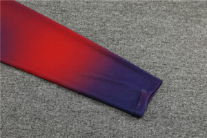 9f2e7de3_1024x1024_2x_541a362d-486e-40ca-ab71-b28740e1afd4 | UAE SPORT STORE Sleeve of a gradient red-to-purple garment laid on a gray carpet, showing the cuff at the end of the sleeve.