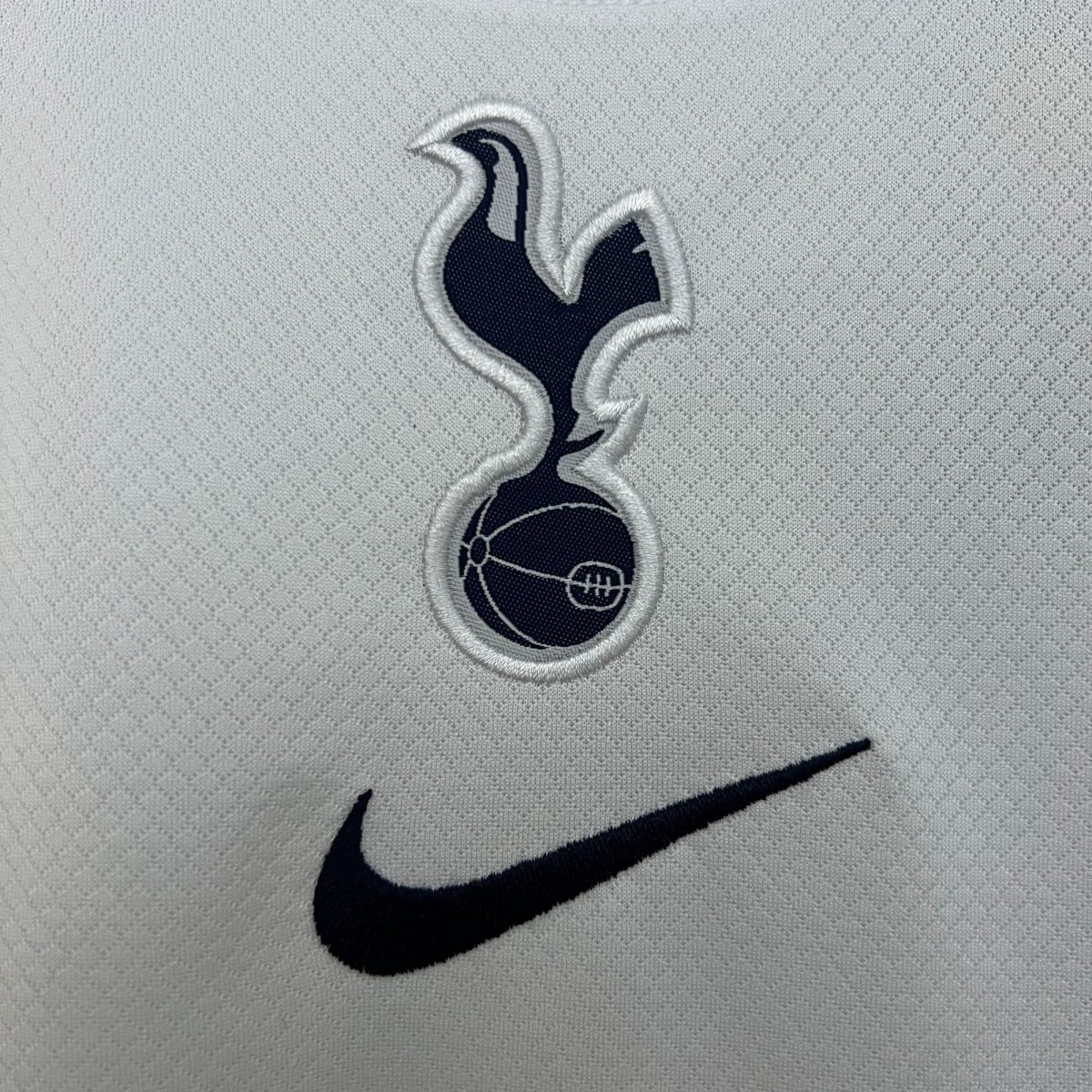 Close-up of a black Nike swoosh embroidered on light gray fabric.