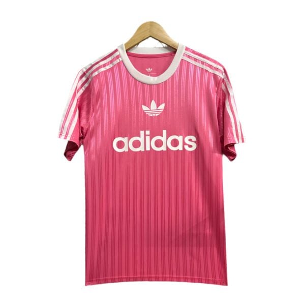 Pink Adidas T-shirt on a hanger with white stripes on shoulders and the Adidas logo and text across the chest.