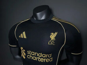 Black Liverpool FC jersey with gold piping and crest, sponsor logo, and Adidas-style stripes displayed on a mannequin.