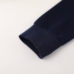 Close-up of navy blue fabric cuff with textured knit and visible seam against a light background, diagonal placement.