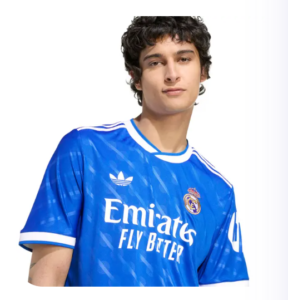 Young man wearing a Real Madrid blue football jersey with Emirates Fly Better logo on the chest.