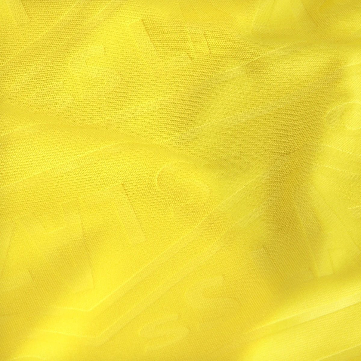 Close-up of bright yellow fabric with soft folds and visible stitching suggests textile texture.