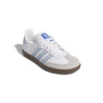 White Adidas sneaker with light blue stripes and a brown gum sole, viewed from an angled side perspective.