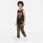 Child wearing a black Jordan jersey with number 23, camouflage pants, and white sneakers, standing against a white background.