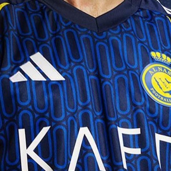 Close-up of a patterned blue Al Nassr jersey with yellow shoulders, club crest and white KAFD sponsor.